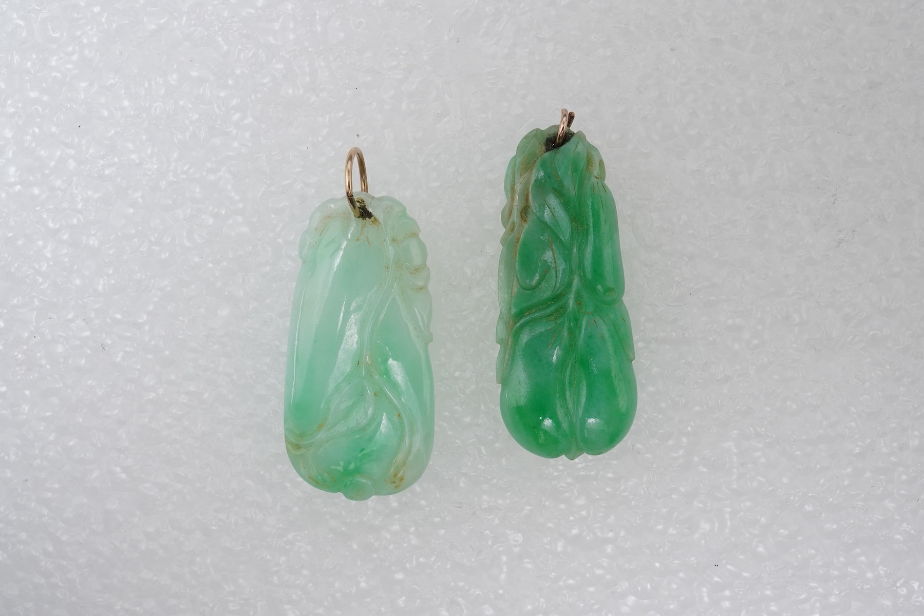 Two carved jadeite pendants, China, early 20th century, each carved to depict a fruiting vine of bitter gourd, longest 3.5cm excluding bail, combined gross weight approximately 10 grams